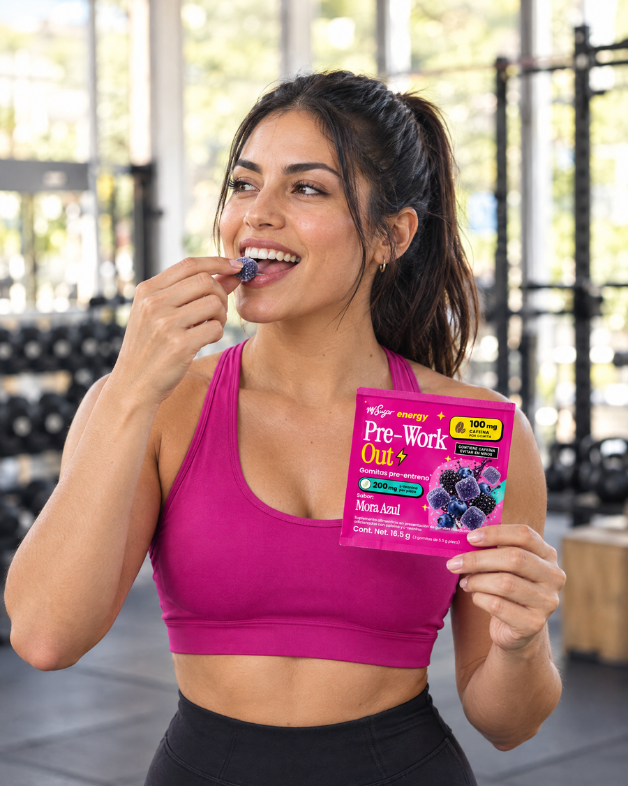Mujer en el gym comiendo una gomita Pre-Work Out Mora Azul con el sobre en la mano