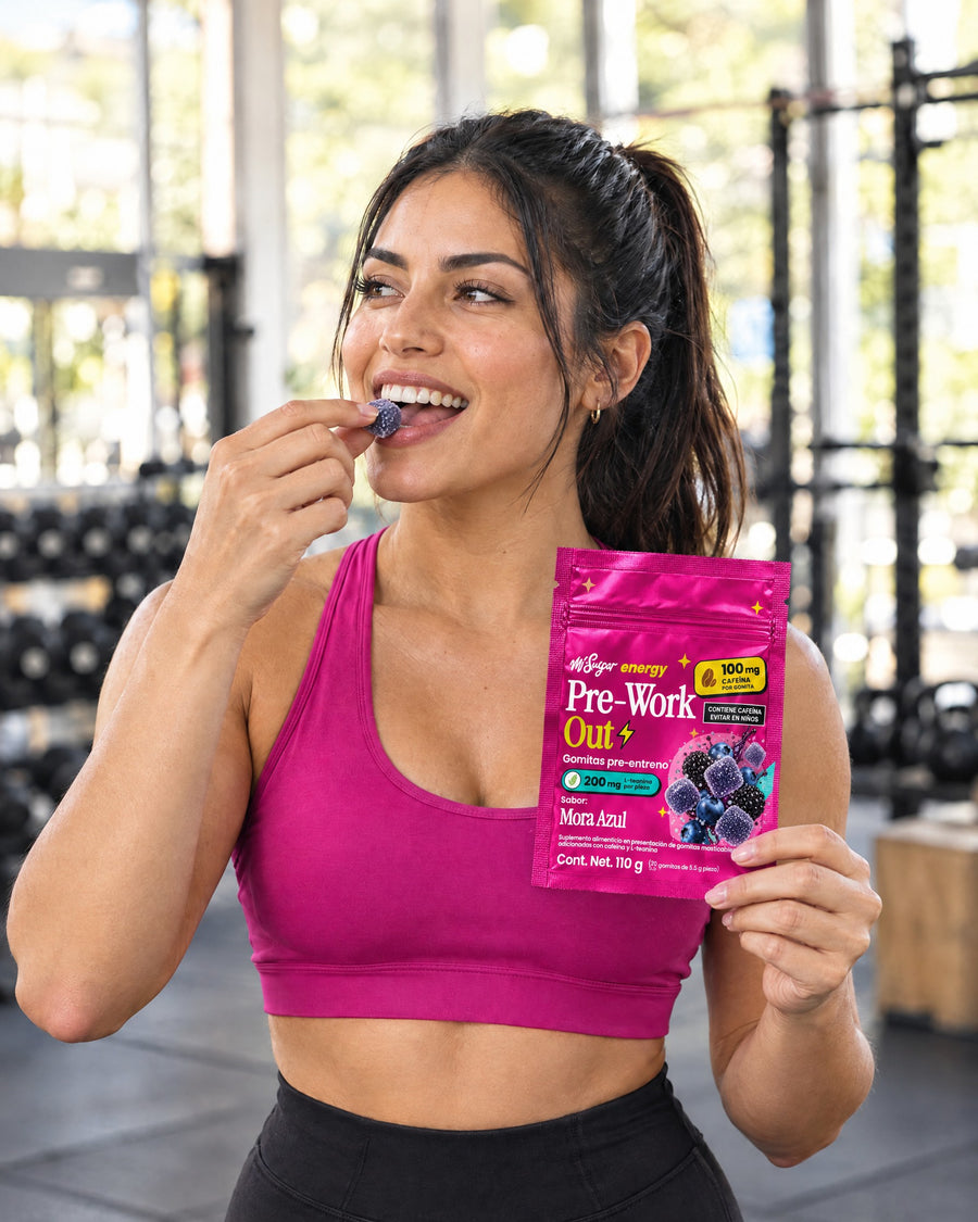 Mujer en el gym comiendo una gomita Pre-Work Out con la bolsa Mora Azul en la mano